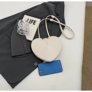 Dettaglio della borsa a cuore bianco panna con doppia cerniera e telefono di confronto