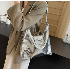 Detail of silver metallic hobo bag featuring chrome bow buckle and chain strap