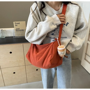 Detail of an orange canvas crossbody bag with a wide strap and cute coffee cup plush charm