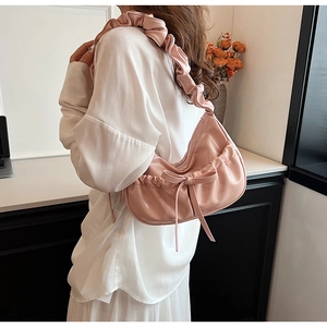 Close-up of pink PU leather hobo bag with ruffled shoulder strap and bow detail