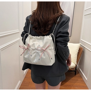 Détail du sac à cordon en PU brillant blanc avec nœuds roses et bandoulière chaîne
