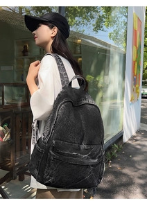 Detail of a large black washed denim backpack with snow wash texture and side pocket
