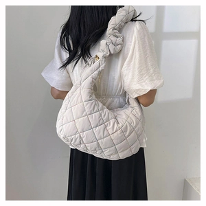 Detailed close-up of light beige quilted crossbody bag with stylish ruffled shoulder strap