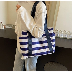 Close-up of blue and white striped tote bag with nylon shoulder strap and side pocket detail