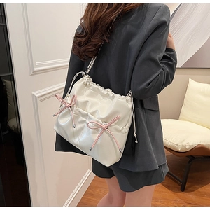 Sac en cuir PU brillant blanc avec nœuds roses et chaîne argentée porté par un modèle