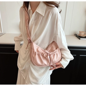 Detail view of pink PU leather crescent bag with cloud pleats and bow tie on model