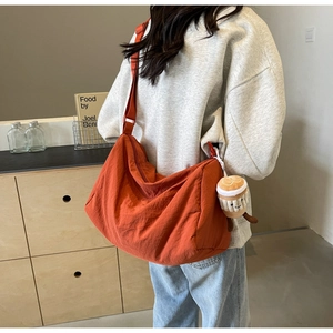 Detail of a spacious orange crescent crossbody bag with a creative coffee cup plush charm