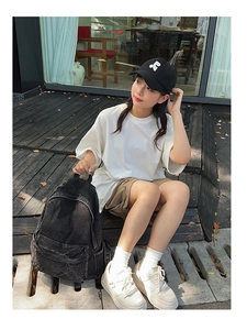 Detailed view of a black washed denim backpack styled in a casual urban street outfit