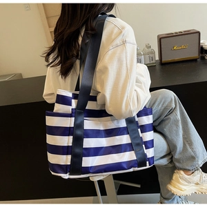 Detail of blue and white striped canvas tote bag showing side pocket and nylon strap