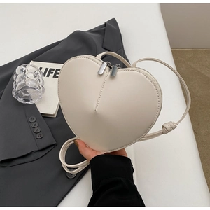 Dettaglio di una borsa a tracolla in pelle PU bianco crema a forma di cuore con zip