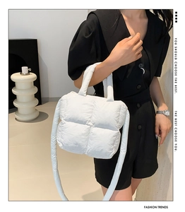 White quilted puffer crossbody bag shown on model in a minimalist modern interior