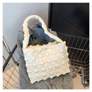 Minimalist white quilted woven handbag with chunky handles in a shopping cart