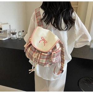 Detail of pink plaid backpack featuring fine butterfly embroidery and drawstring closure