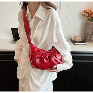 Close-up of red glossy PU leather handbag with elegant bow and pleated cloud texture