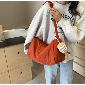 Detail of warm orange canvas crossbody bag with plush coffee cup charm and wide strap