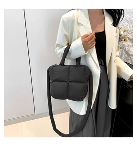 Detail of a black quilted puffy crossbody bag with soft padded handles and strap