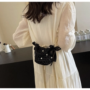 Close-up of handmade black crochet mini crossbody bag with white pearls and bow detail