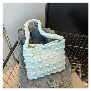 Light blue quilted puffer handbag with woven texture placed in a metal shopping cart