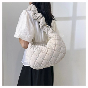 Detail of a quilted nylon crossbody bag with ruffled shoulder strap worn by a model