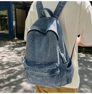 Outdoor street shot of a woman wearing a casual washed blue denim backpack with pockets