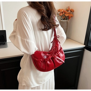 Detail of red crescent PU leather bag with bow accent and trendy pleated design