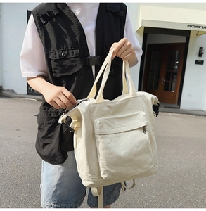 Cream canvas multi-way backpack with large front pocket styled on a model in urban setting