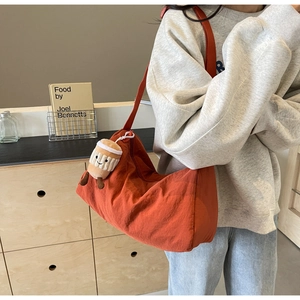 Detail view of brick red crescent crossbody bag with cute plush coffee cup charm