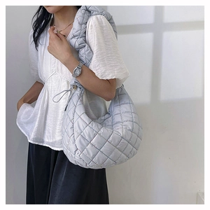 Detail of light blue quilted nylon hobo bag with stylish ruffled shoulder strap design