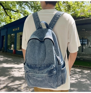 Outdoor shot of a vintage washed denim backpack featuring large front pocket and side pockets
