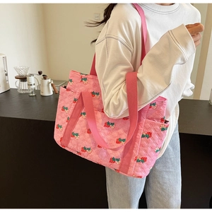 Detailed view of the strawberry quilted tote bag side pocket and pink fabric texture