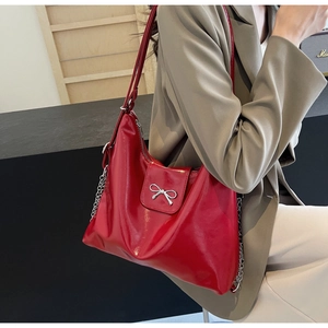 Detail of red PU leather hobo bag with silver bow ornament and chain strap detail