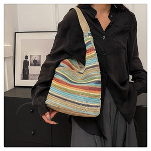 Close-up of rainbow striped knit handbag with beige leather strap and reinforced base
