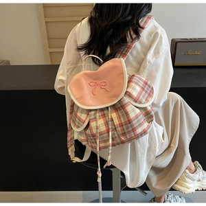 Detail of checkered canvas backpack with pink leather flap and embroidered bow accent