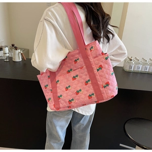 Detail of pink quilted tote bag with strawberry pattern and convenient side pocket