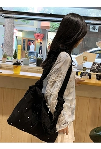 Close-up of a black nylon tote bag with white rivet details and large capacity design
