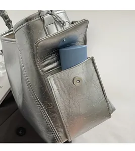 Detail of silver metallic PU tote bag showing side functional pocket with magnetic buckle