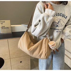 Detail of khaki nylon crossbody bag with a cute plush coffee cup charm on female model