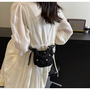 Detail of black woven crossbody bag with pearls and silk bows on a model