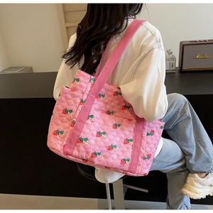 Detail shot of pink quilted tote bag with strawberry print and wide canvas shoulder strap