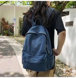 Outdoor view of a durable blue denim backpack with front pocket and spacious compartments