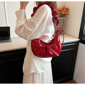 Detail of red PU leather crescent shoulder bag with ruffle accents and bow design