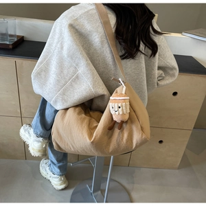 Detail view of large beige canvas hobo bag with a cute coffee cup plush pendant