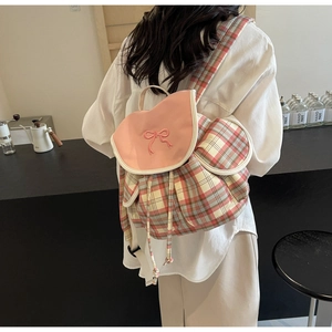 Detail of pink plaid backpack with embroidered bow and drawstring closure on a canvas bag