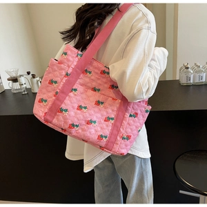Detailed shot of a pink quilted strawberry tote bag in a cozy cafe setting