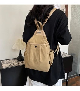 Gros plan du sac à dos en nylon kaki sur modèle montrant le design multipoches