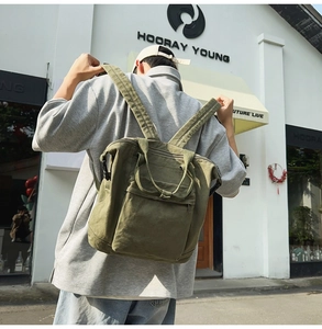 Close-up of military green canvas backpack with top handle and front zipper pocket