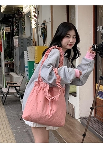 Pink pleated nylon tote bag featuring ruffled shoulder straps and drawstring closure