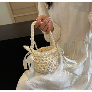Detail of woven fabric handbag with white pearls and satin ribbon bows for women