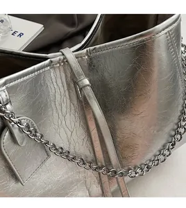 Detail of silver metallic PU crossbody bag showing pleated texture and chain strap