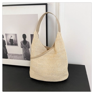 Minimalist beige knitted summer tote bag with brown PU leather straps on a dark surface